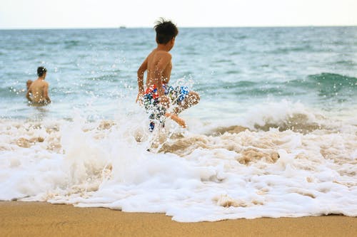 男孩冲向大海的照片 · 免费素材图片