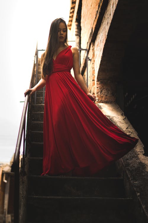 女人穿着红色的裙子站在楼梯上 · 免费素材图片