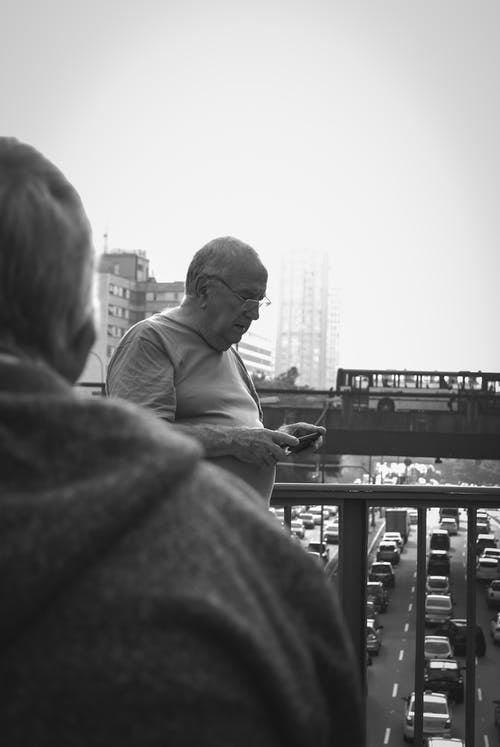 男子手持智能手机的灰度摄影 · 免费素材图片