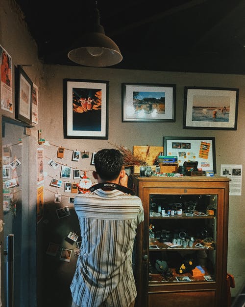 满是照片的墙上拍照的人 · 免费素材图片