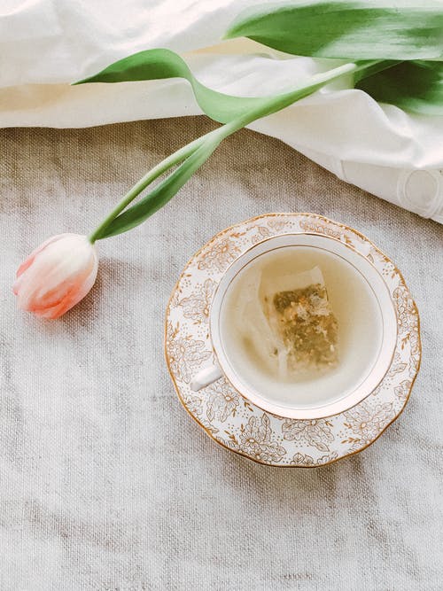 茶杯和茶碟附近的粉红色花瓣的花朵 · 免费素材图片