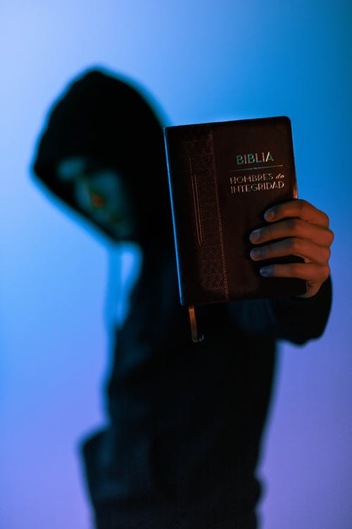 男子手持圣经的选择性焦点摄影 · 免费素材图片