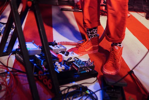 在键盘脚架附近的吉他踏板控制器附近的人 · 免费素材图片