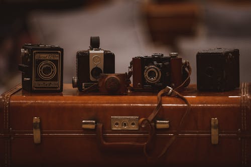 棕色手提箱上的四个彩色照相机 · 免费素材图片