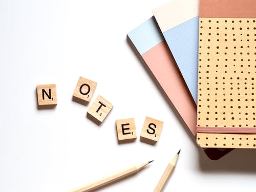 两个铅笔旁边的五个棕色木制拼字砖 · 免费素材图片