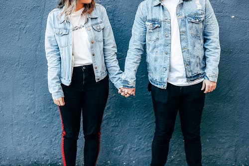 两个人站在蓝色的墙壁旁边，手牵着手 · 免费素材图片