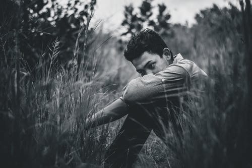 人坐在草地上的单色照片 · 免费素材图片