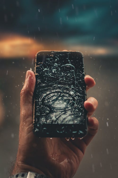 拿着湿的智能手机的人的照片 · 免费素材图片