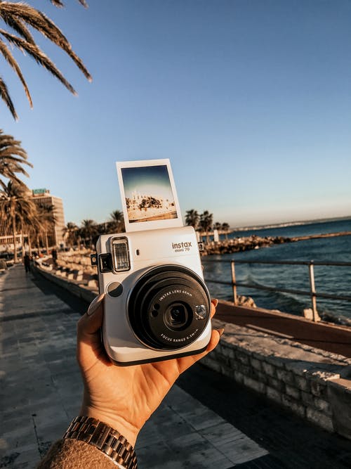 持有instax Mini 70的人在海边 · 免费素材图片