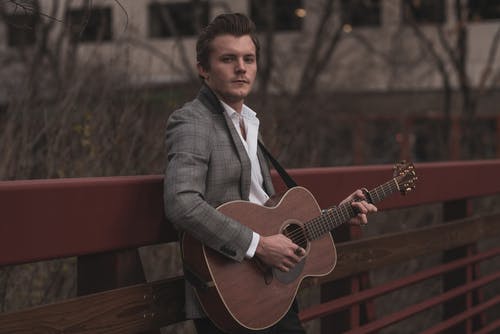 弹吉他时靠在扶手上的男人 · 免费素材图片