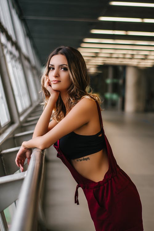 女人靠在灰色的栏杆上 · 免费素材图片