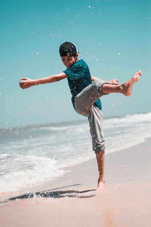 男孩在岸上踢沙 · 免费素材图片