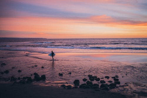 站在岸上抱着冲浪板的人 · 免费素材图片