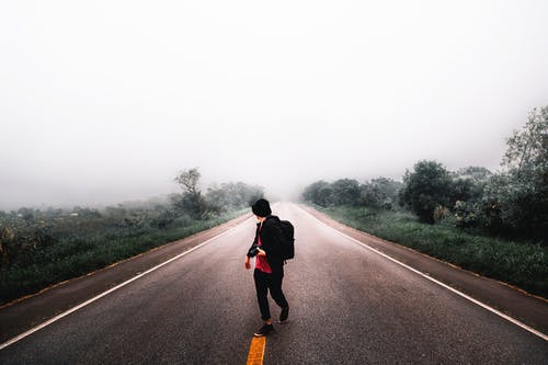 在白色的天空下的草地之间的道路中间的人瓦林 · 免费素材图片