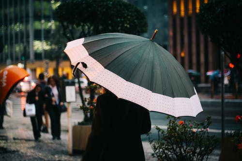 女人拿着伞走在大街上的选择性焦点摄影 · 免费素材图片