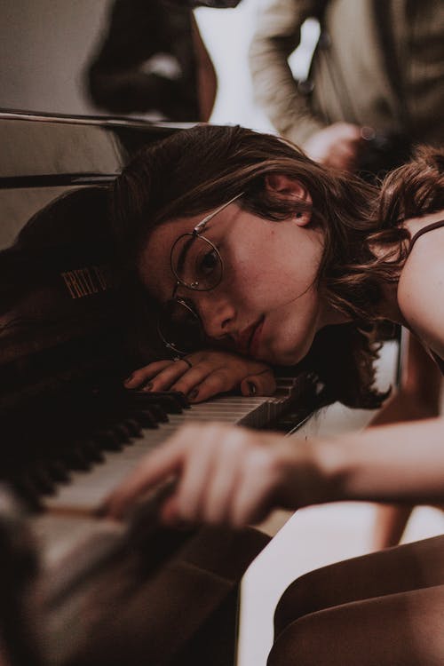 戴着灰色镜框的眼镜弹钢琴的女人 · 免费素材图片