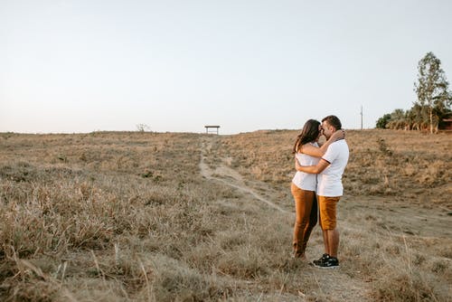 夫妇在棕色草田拥抱 · 免费素材图片