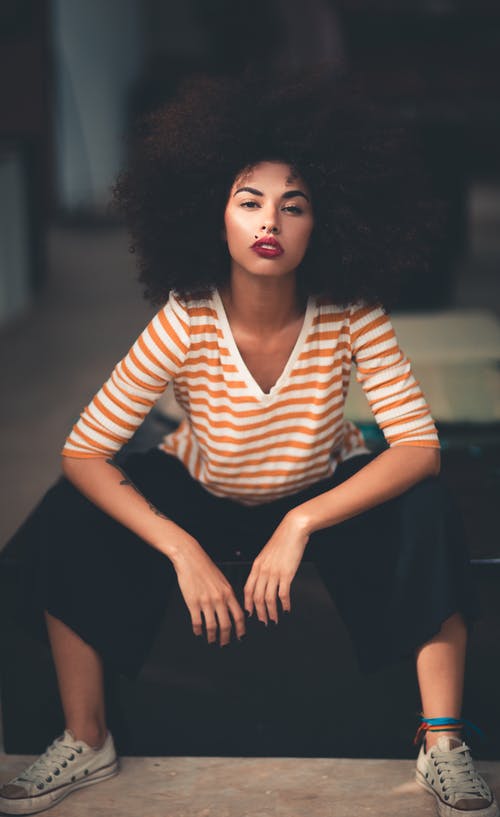 女人坐穿橙色和白色的v领条纹的肘袖的衬衫 · 免费素材图片