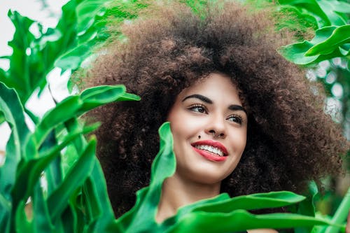 微笑在绿叶植物旁边的女人 · 免费素材图片