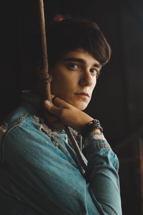 男人穿着蓝色牛仔夹克拿着棕色的绳子特写照片 · 免费素材图片