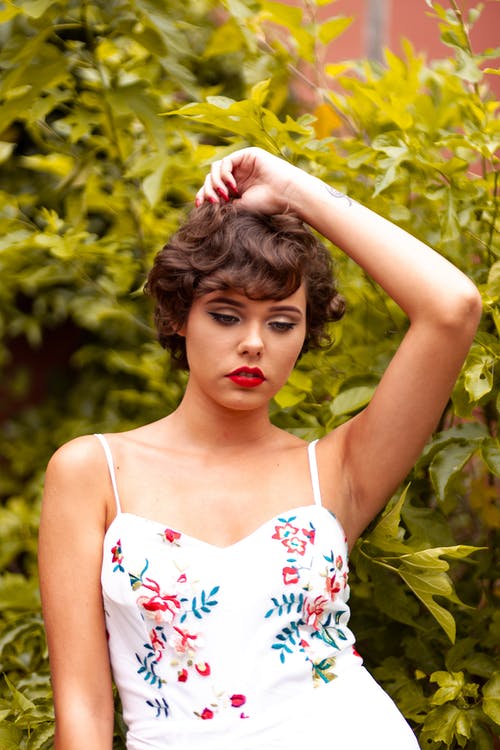 女人穿着白色意大利面条皮带顶摆在植物旁边 · 免费素材图片