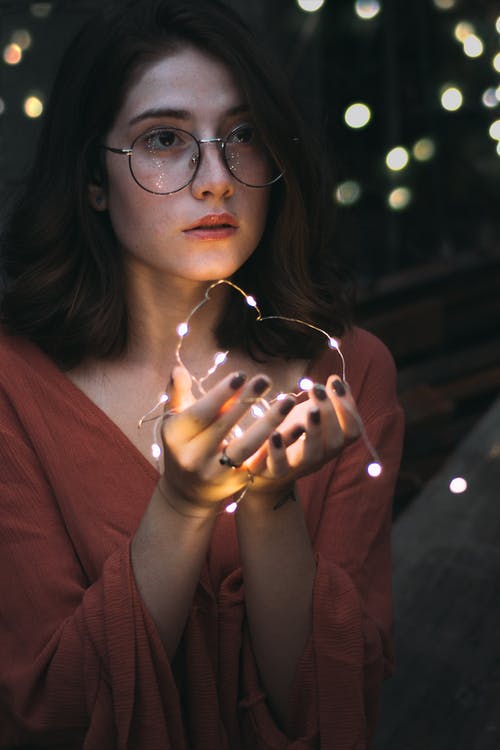 女人拿着灯串的选择性聚焦摄影 · 免费素材图片