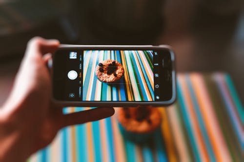 使用智能手机拍照的巧克力蛋糕的人 · 免费素材图片