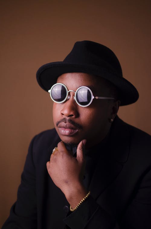 男子戴着灰色圆形镜框的太阳镜，拿着下巴特写照片 · 免费素材图片