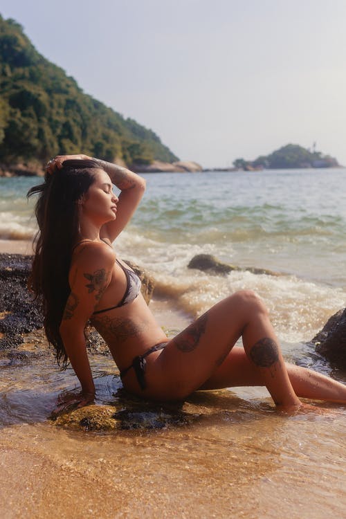 比基尼泳装，坐在岸上的女人 · 免费素材图片