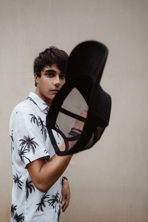 男子手持黑帽子 · 免费素材图片