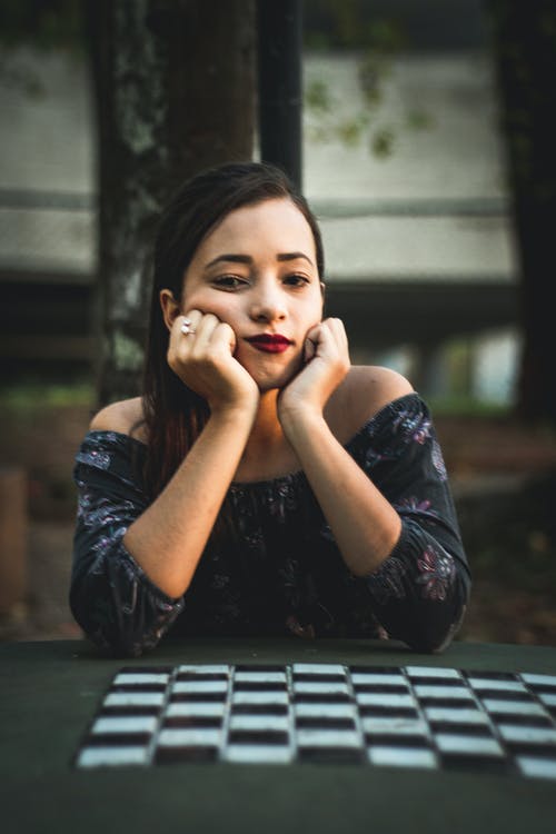 女人坐在象棋桌旁边用手在下巴上 · 免费素材图片