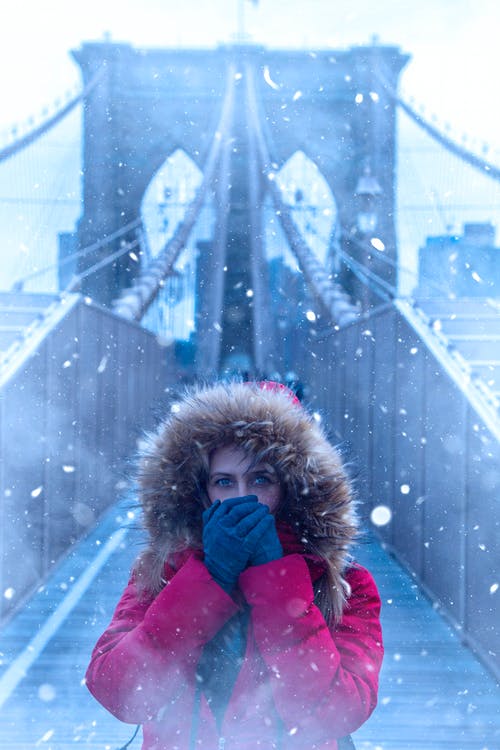 女人站在布鲁克林大桥上身穿红色风衣外套 · 免费素材图片