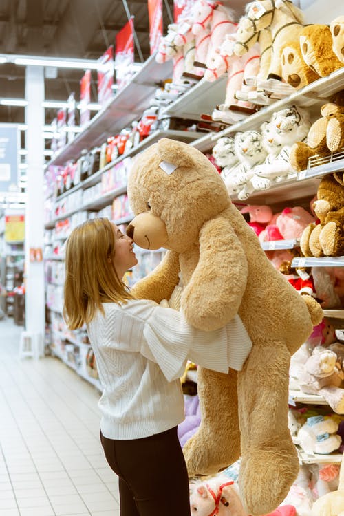 女人携带熊毛绒玩具店内 · 免费素材图片
