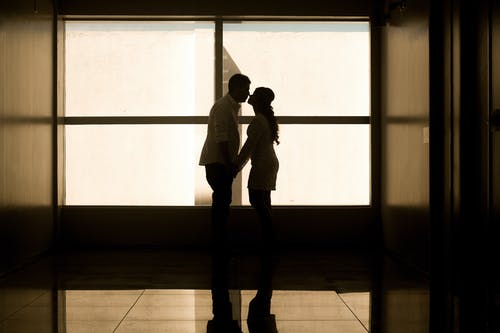 男人和女人手牵着手在玻璃窗附近 · 免费素材图片