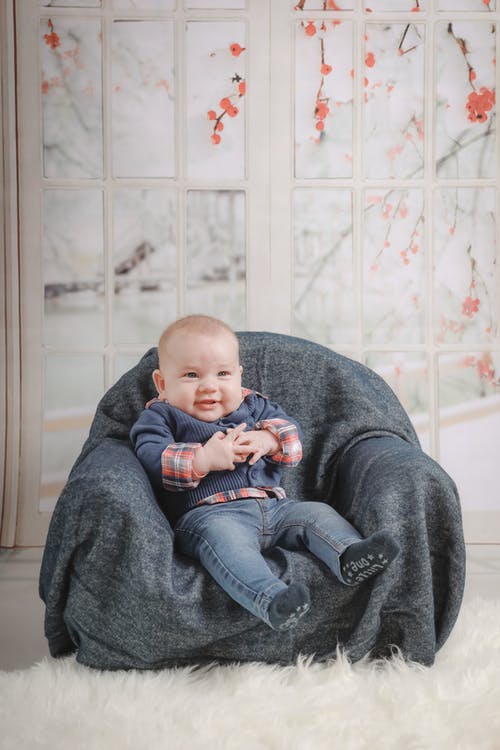 婴儿坐在沙发上的椅子上 · 免费素材图片