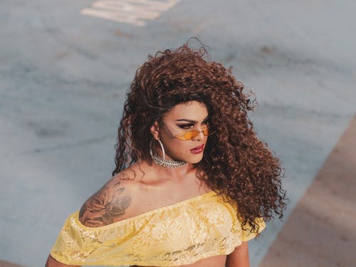 女人站着黄色的作物顶部和太阳镜的照片 · 免费素材图片