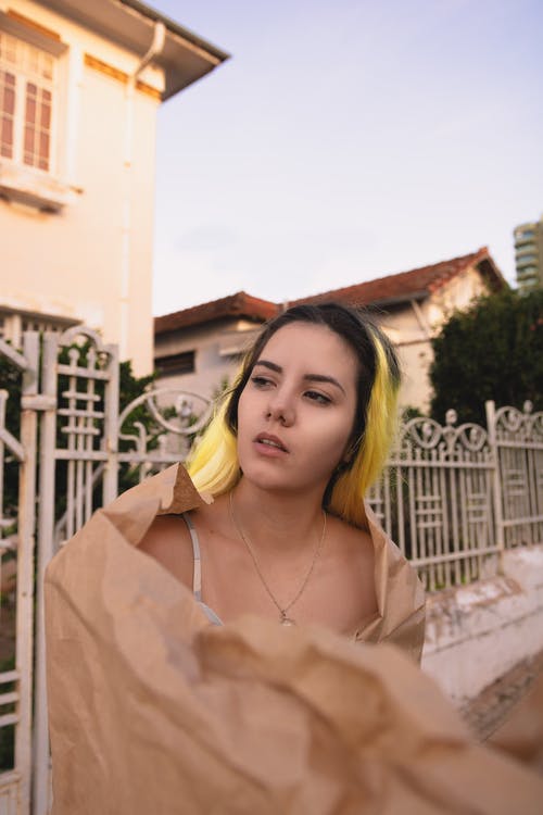 用牛皮纸包裹的黄色高光的女人的照片 · 免费素材图片