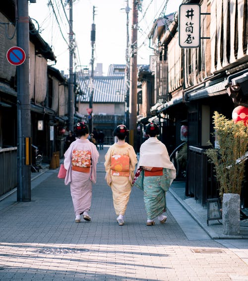 三个女人穿着传统服饰在大街上行走 · 免费素材图片