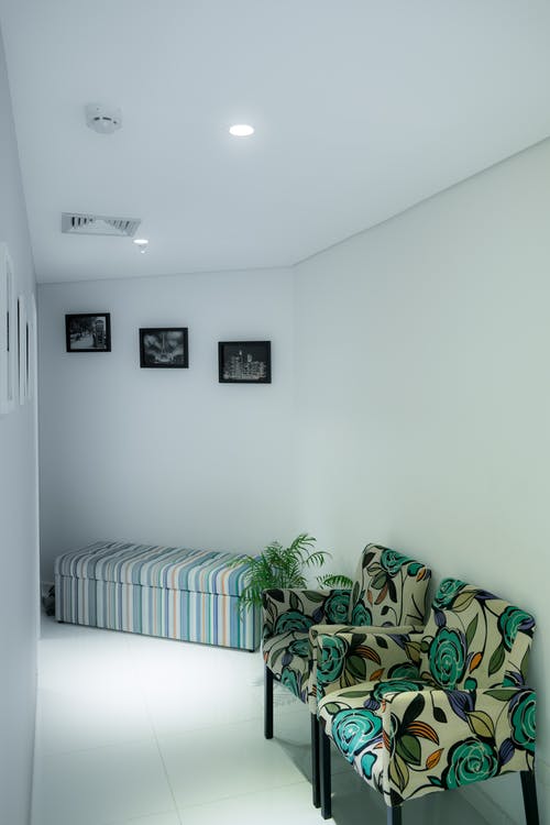 房间墙壁旁边的两把白色和绿色碎花软垫沙发椅 · 免费素材图片