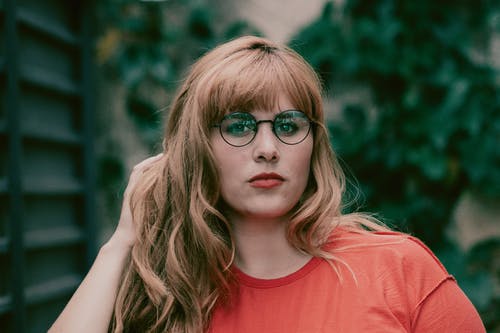 眼镜用左手抚摸她的头发的女人的照片 · 免费素材图片