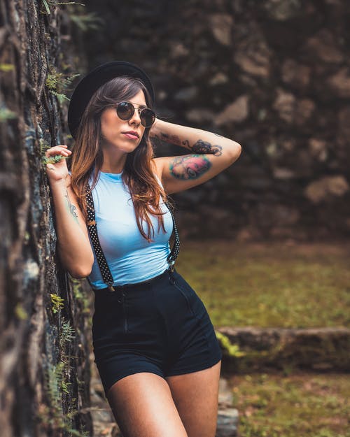 女人戴着帽子靠在栅栏上 · 免费素材图片