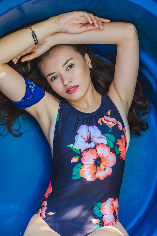躺着用手在头上的蓝色花卉一件泳装躺着的女人的照片 · 免费素材图片