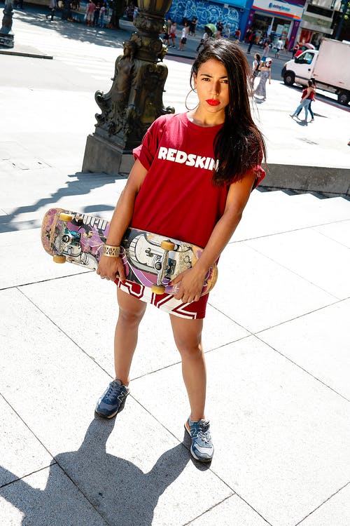 女人穿着红色衬衫拿着滑板 · 免费素材图片