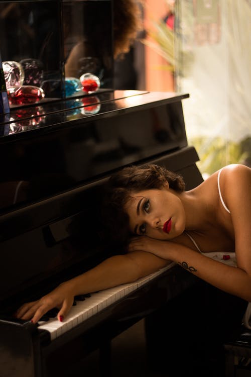 躺在棕色木制钢琴上的女人 · 免费素材图片