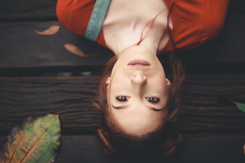 躺在褐色的木质表面上的女人 · 免费素材图片