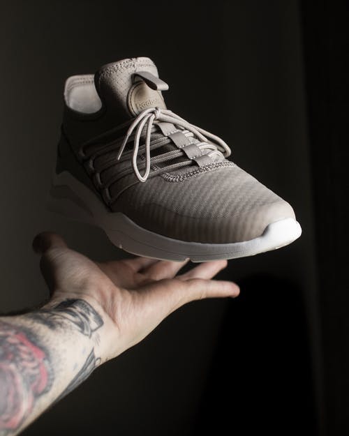 手指上的灰色和白色adidas低帮运动鞋 · 免费素材图片