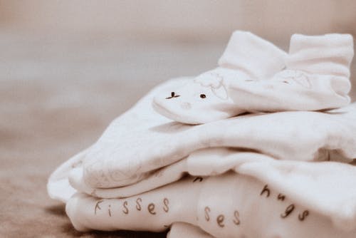 一双婴儿的白色袜子在白色纺织品上 · 免费素材图片