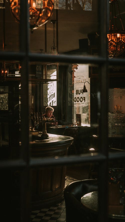 坐在一个舒适的老酒吧的桌子上的孤独的人 · 免费素材图片