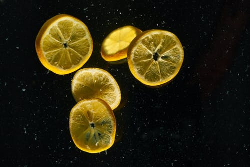 切成薄片的黑色表面上的柠檬 · 免费素材图片