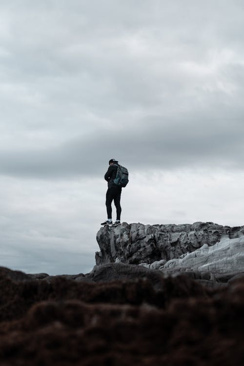 背包里站在悬崖上的男人 · 免费素材图片